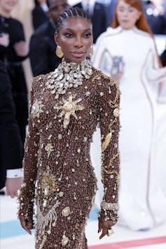 Michaela Coel in a bejewelled dress and large gold earrings.