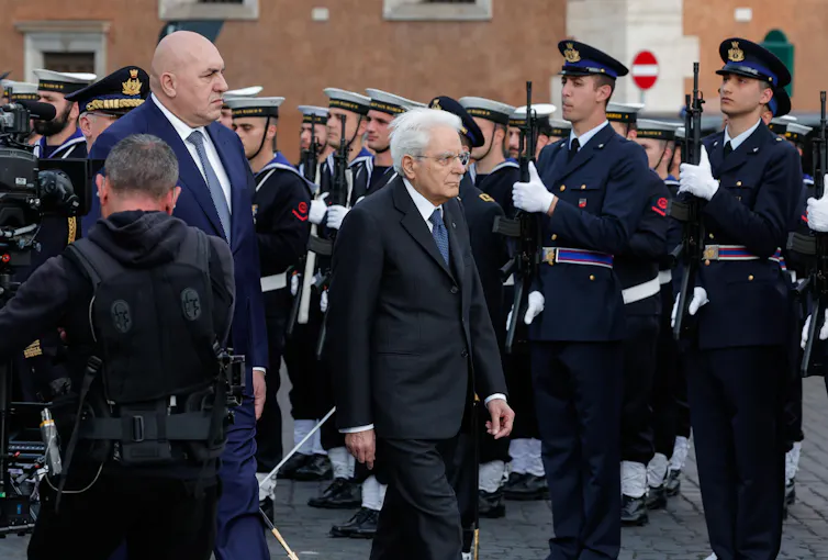 Sergio Mattarella walking in front of troops standing to attention.