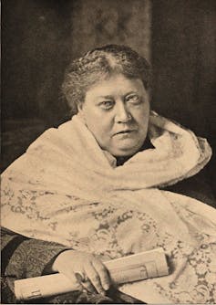 A sepia-toned portrait of an older woman wearing a white shawl and clutching a scroll.