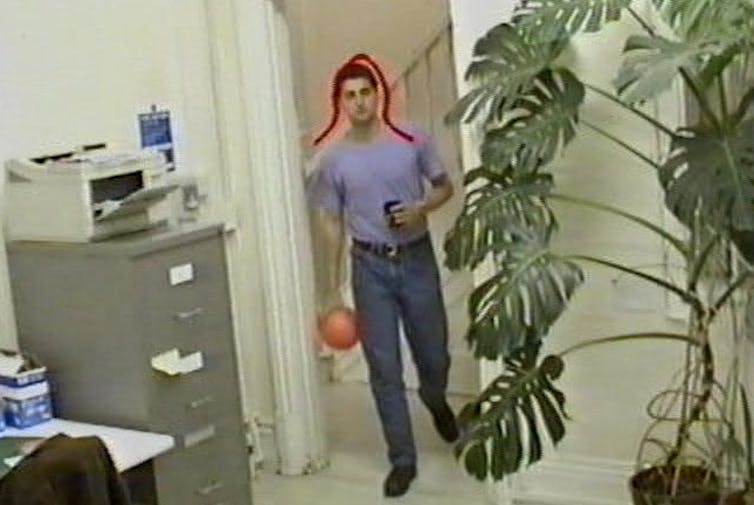 un cuadro de video en color que muestra a un joven que ingresa a una habitación con una curva roja superpuesta a la imagen que delinea su cabeza