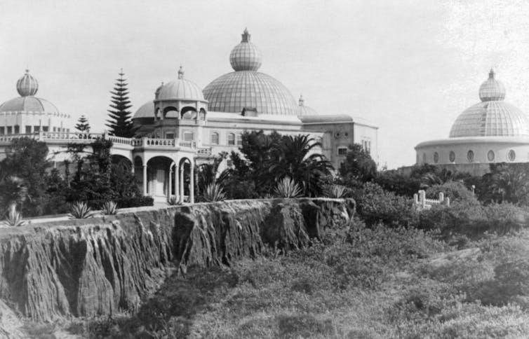 A black and white photograph of ornate white buildings with domed roofs.
