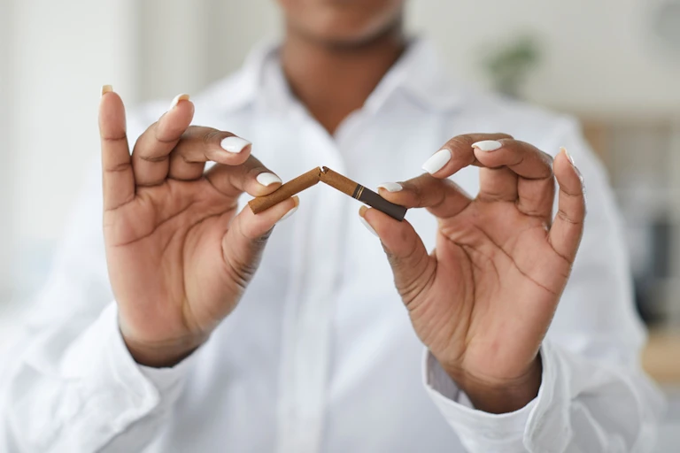 Woman breaking cigarette in half, palms forward