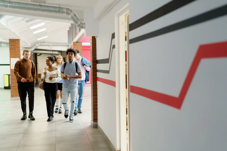 Five students walk down a corridor.