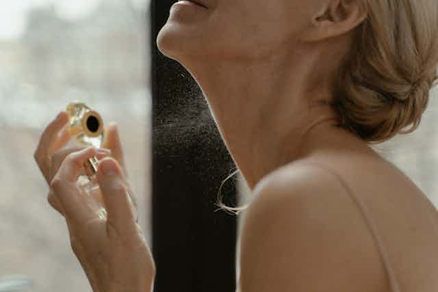 woman sprays perfume on neck