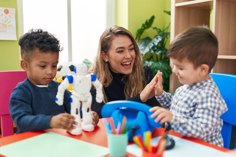 Un niño juega con un robot mientras otro niño interactúa con la maestra.