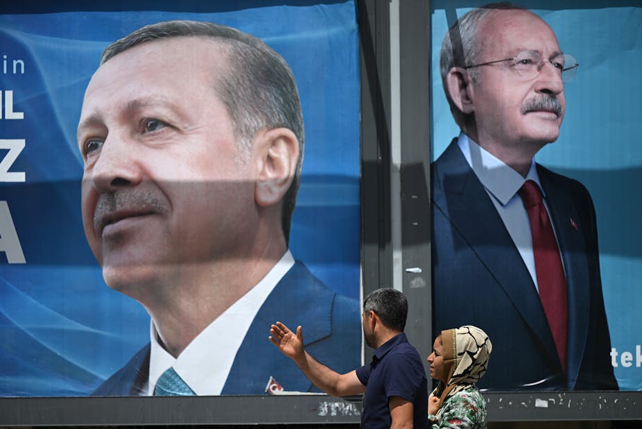 Un couple passe devant des panneaux d'affichage portant le portrait du président turc Recep Tayyip Erdogan (à gauche) et celui du leader du Parti républicain du peuple (CHP) et candidat à la présidence, Kemal Kilicdaroglu (à droite), à Sanliurfa, dans le sud-est de la Turquie, le 28 avril 2023.