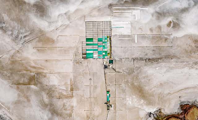 Vue satellite d'un desert de sel, au centre duquel on voit un quadrillage d'une cerntaine de rectangles, dont certains sont remplis d'une eau bleu/verte.