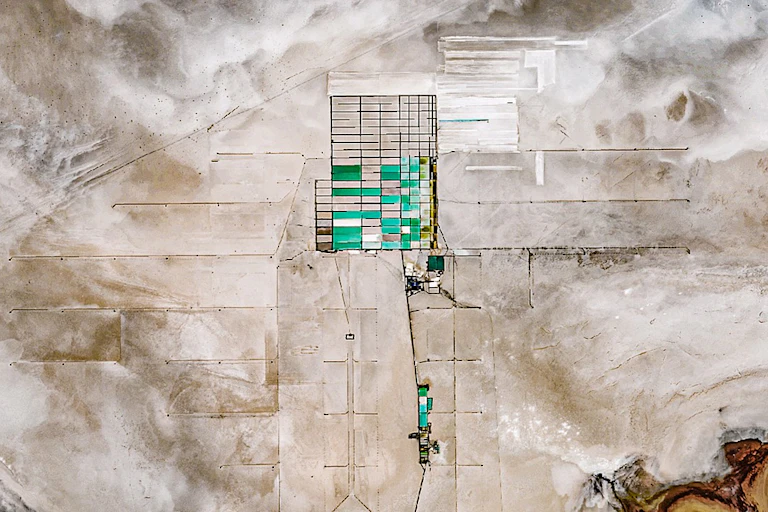 Vue satellite d'un desert de sel, au centre duquel on voit un quadrillage d'une cerntaine de rectangles, dont certains sont remplis d'une eau bleu/verte.