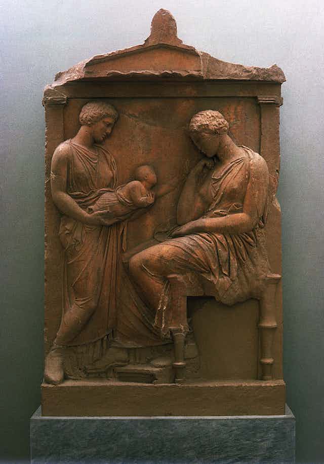 A carved relief shows two women looking at a baby that one of them is holding.