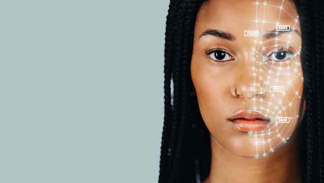 a young Black woman with long braided hair facing the camera with a web of white lines on the left side of her face