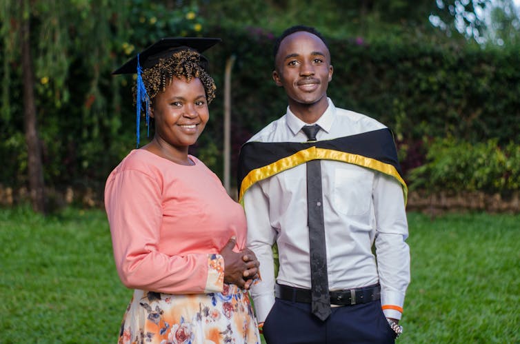 a smiling woman seen next to a young person in a graduation cap.