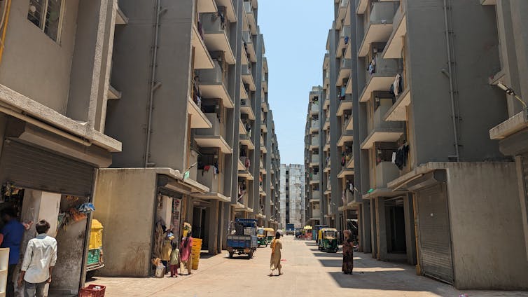 7 storey apartment building painted grey with shops and parking on ground level