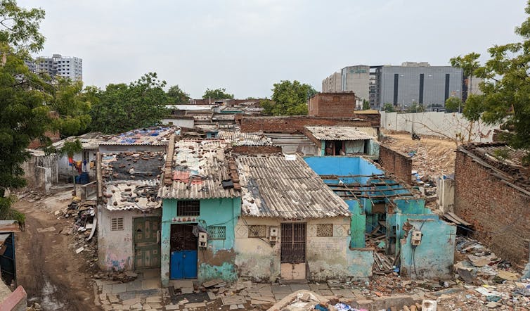 View of roofs in Ramapir No Tekro showing demolition of houses and construction site in background.