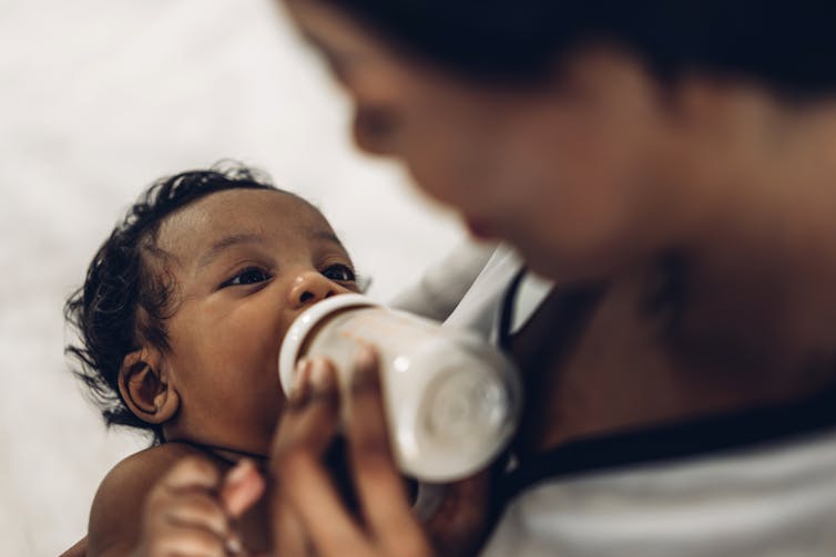 A woman feeding a baby from a bottle.