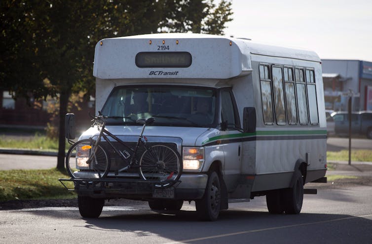 A transit bus with a bike on a bike rack attached to the front of the vehicle.