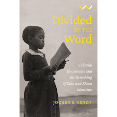 A book cover showing an old photo of a young African girl in western attire holding a book and a pen and reading from the pages.