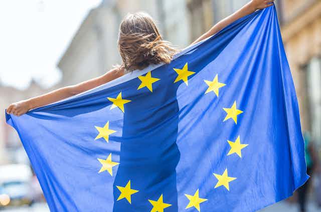 Jovencita de espaldas con la bandera de la Unión Europea.