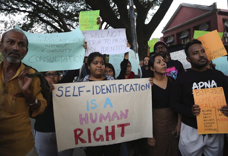 A woman at a protest holds a placard that reads: self identification is a human right.