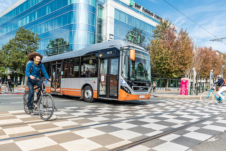 Un autobús y un ciclista cruzando los raíles del tranvía.