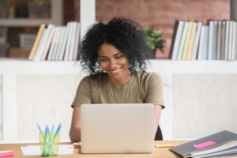 A woman smiling and looking at her laptop screen