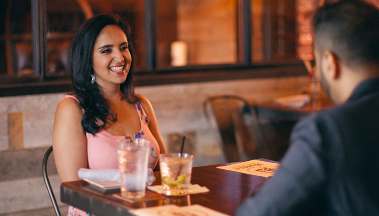Smiling woman sitting at a restaurant with a date.