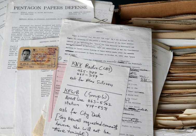 A pile of old papers, mostly typed with handwritten notes on them, and an ID card.
