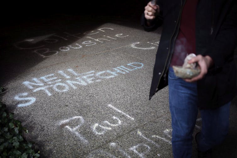 A patch of pavement with the names of victimized Indigenous people drawn in chalk, including Neil Stonechild.