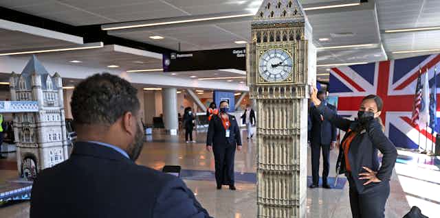 A woman poses next to a watchtower replica in an airport.