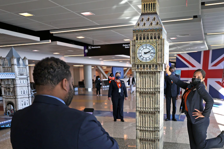 A woman poses next to a watchtower replica in an airport.