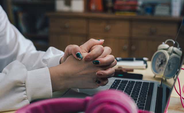 white woman's hands are seen folded over a  laptop keyboard
