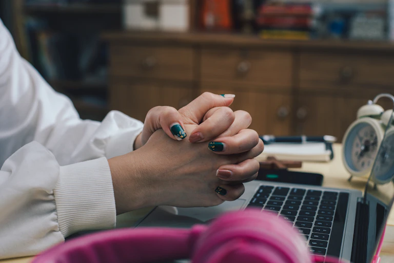 white woman's hands are seen folded over a laptop keyboard
