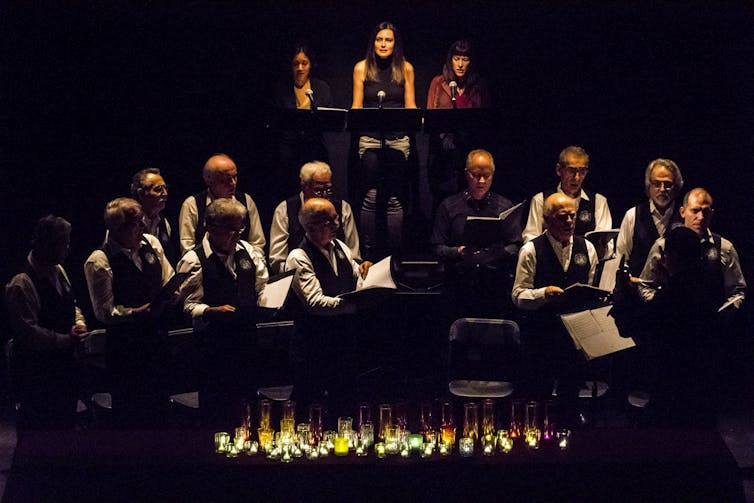 A line of people seen on stage against a dark background.