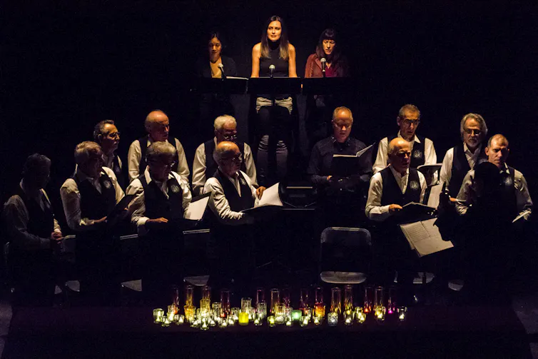 A line of people seen on stage against a dark background.