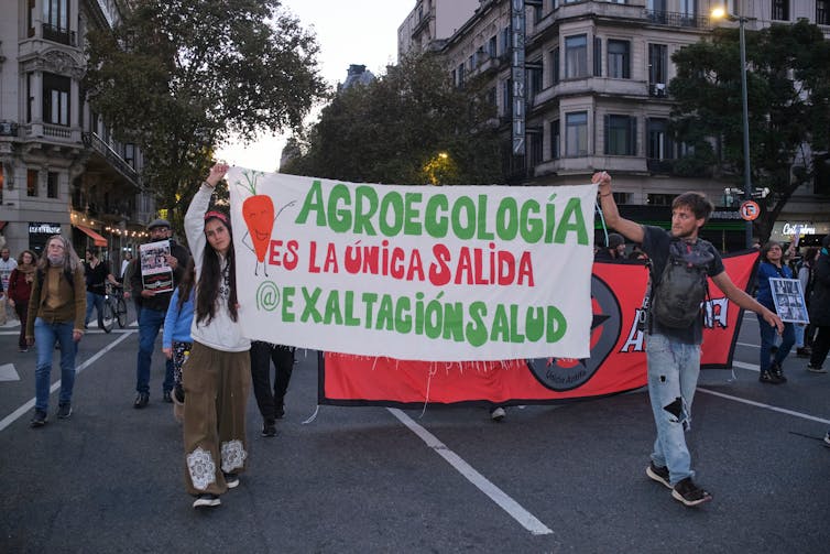 people march in protest holding sign in Spanish