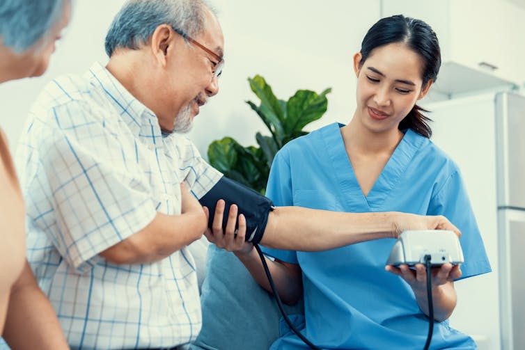 Clinician takes an elderly man's blood pressure with a machine