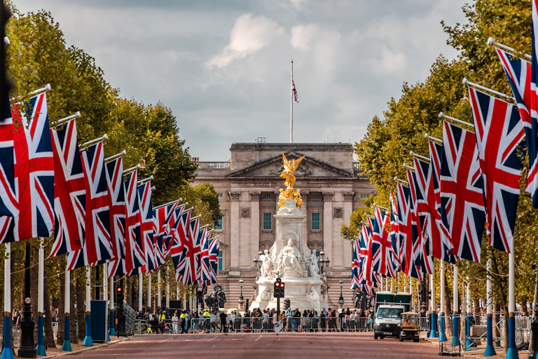 View of Victoria fountain and Buckingham Palace from the mall, which is lined with Union Jack flags on either side