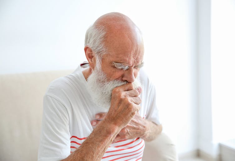 Older adult coughing.
