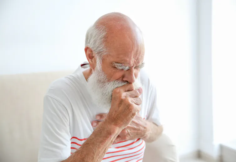 Older adult coughing.