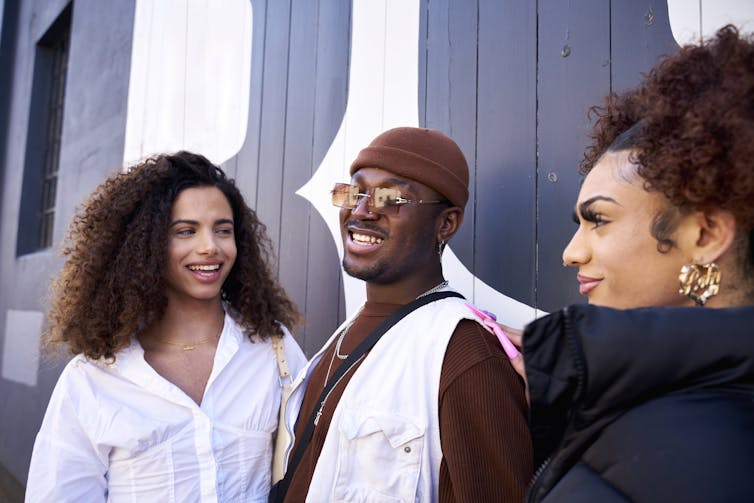 Three young adults smile and pose together