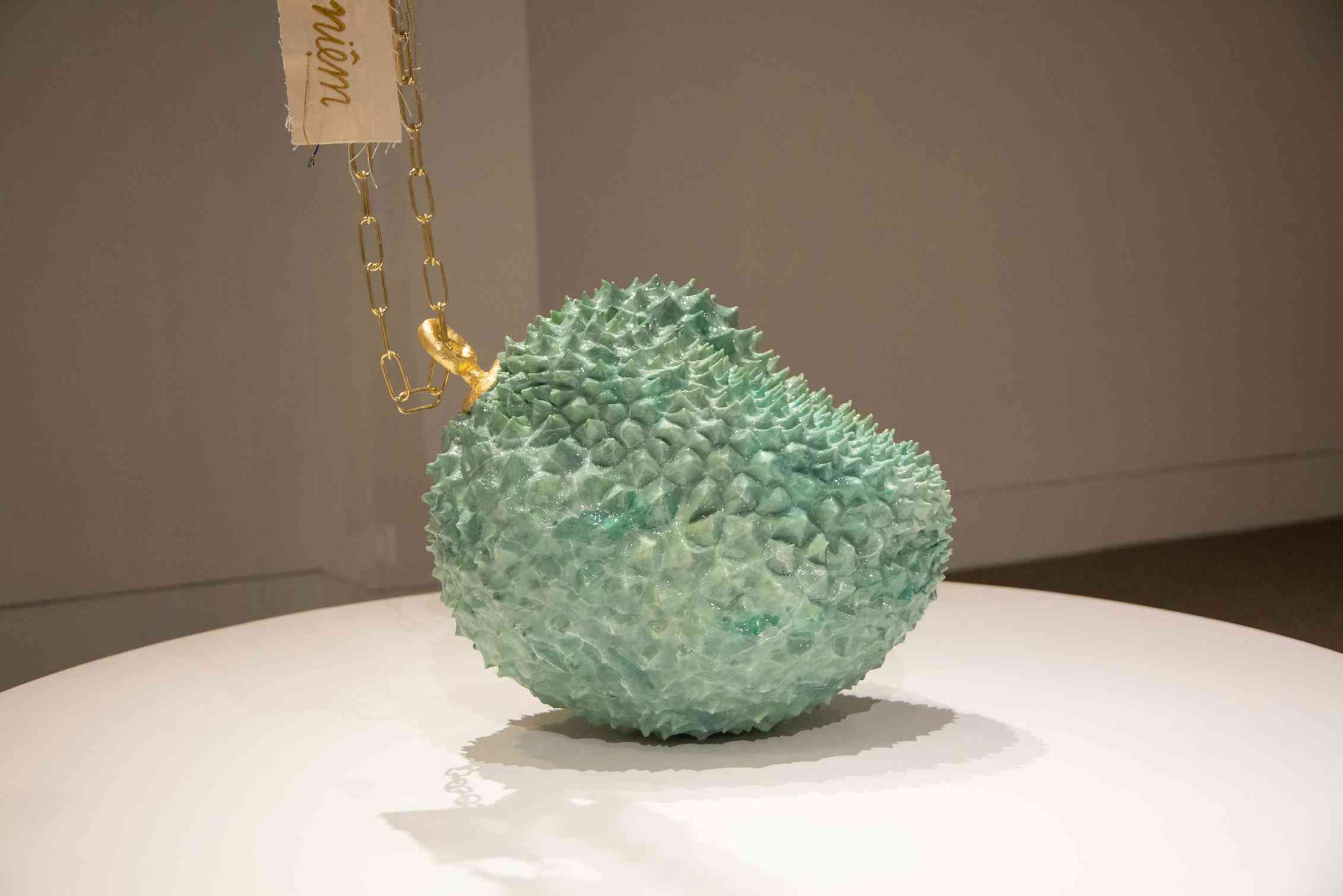 A sculpture of a durian fruit painted green.