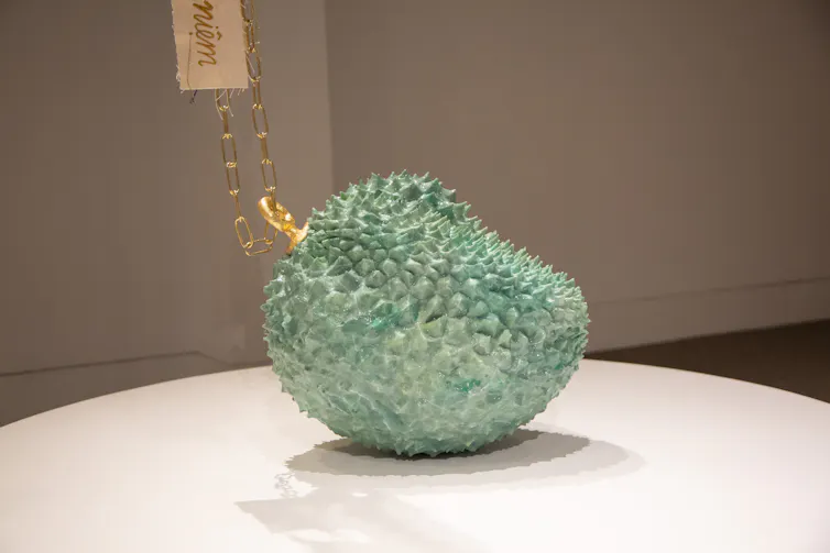 A sculpture of a durian fruit painted green.