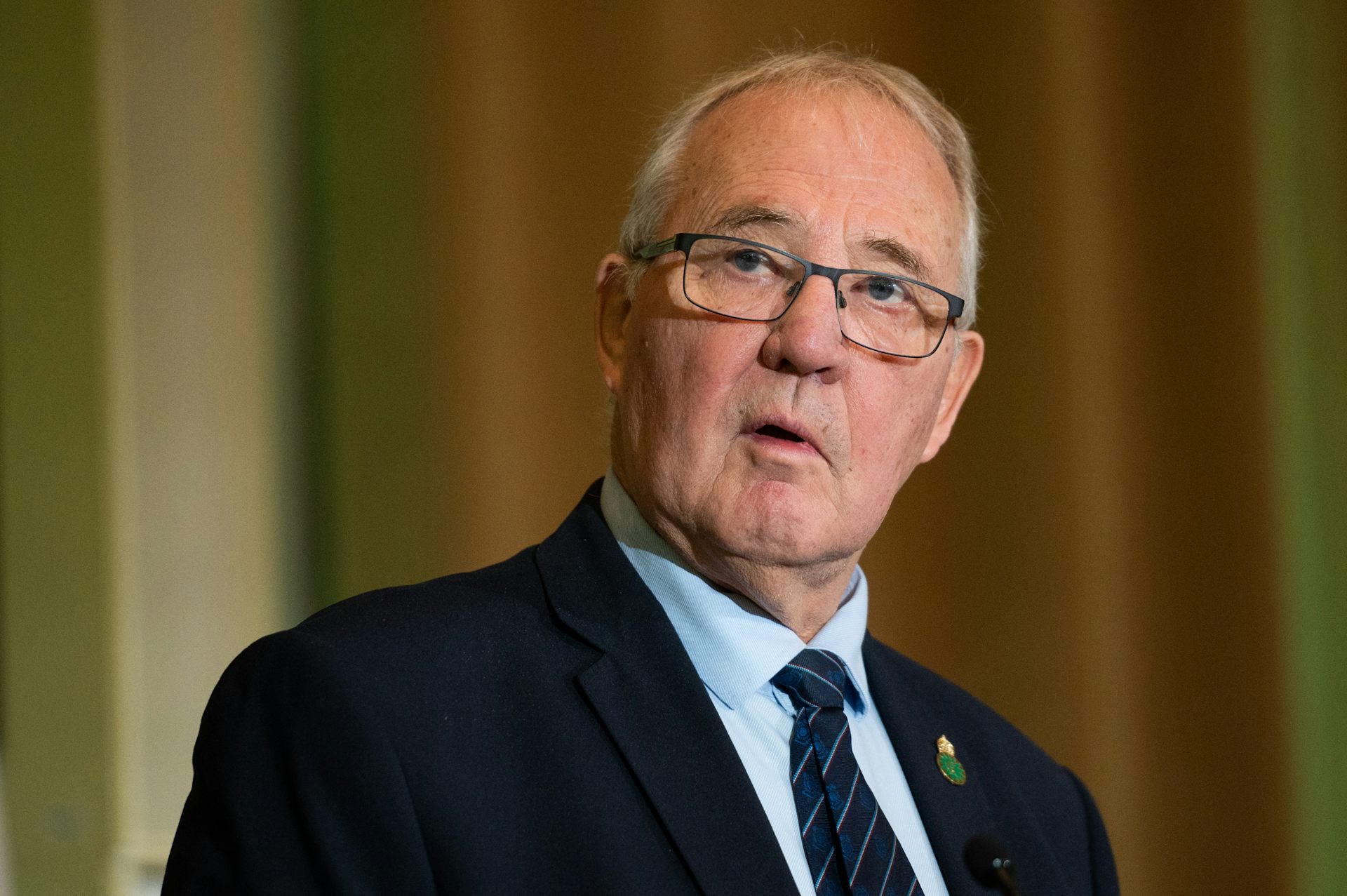 A man in glasses and a dark suit.