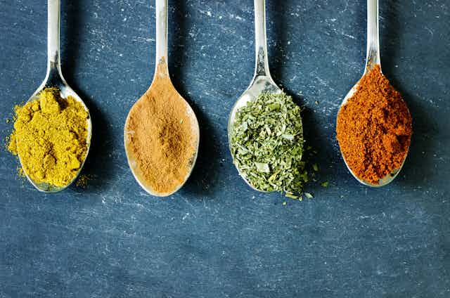 Spoons full of yellow, orange, green and red spices