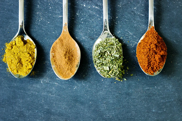 Spoons full of yellow, orange, green and red spices