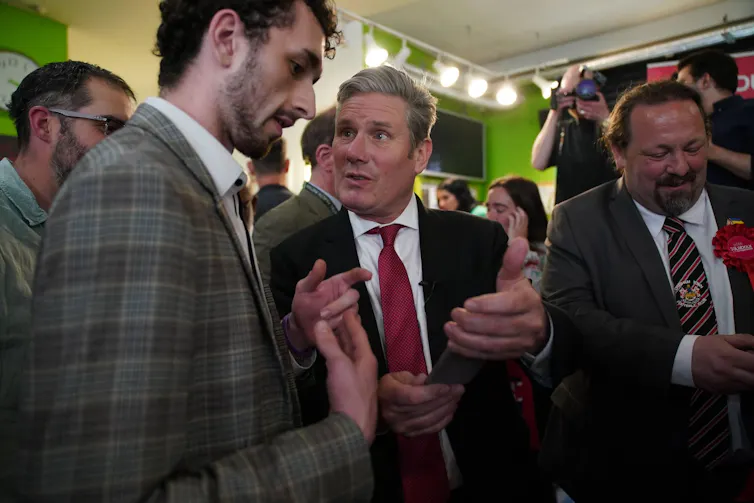 Keir Starmer showing a man a phone at a gathering of people