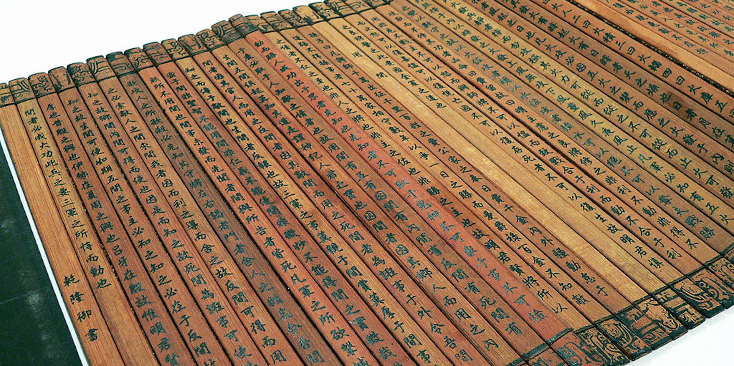 Many thin planks of bamboo tied together to form a book, with Chinese characters written on them.