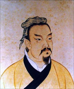 A weathered painting of an Asian man with a small beard and mustache, wearing a yellow and black robe.