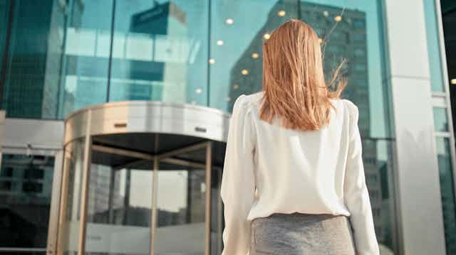 Women in business clothing approaching revolving door of office building