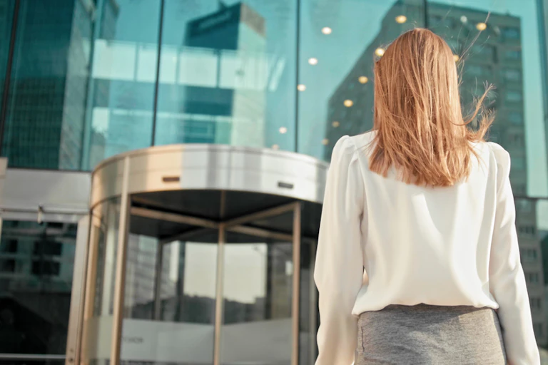 Women in business clothing approaching revolving door of office building