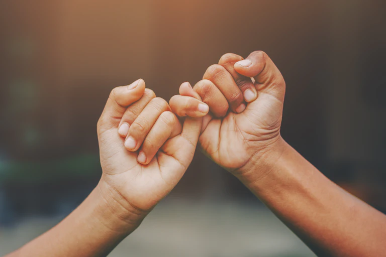 Two hands linking their little fingers